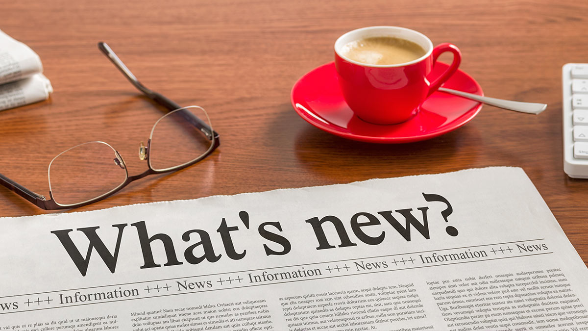 Image of newspaper, reading glasses and a small red cup of coffee.